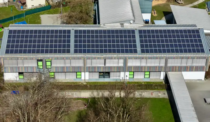 Großflächige Solaranlage mit Photovoltaik-Modulen bei Sonnenuntergang unter dramatischem Wolkenhimmel.